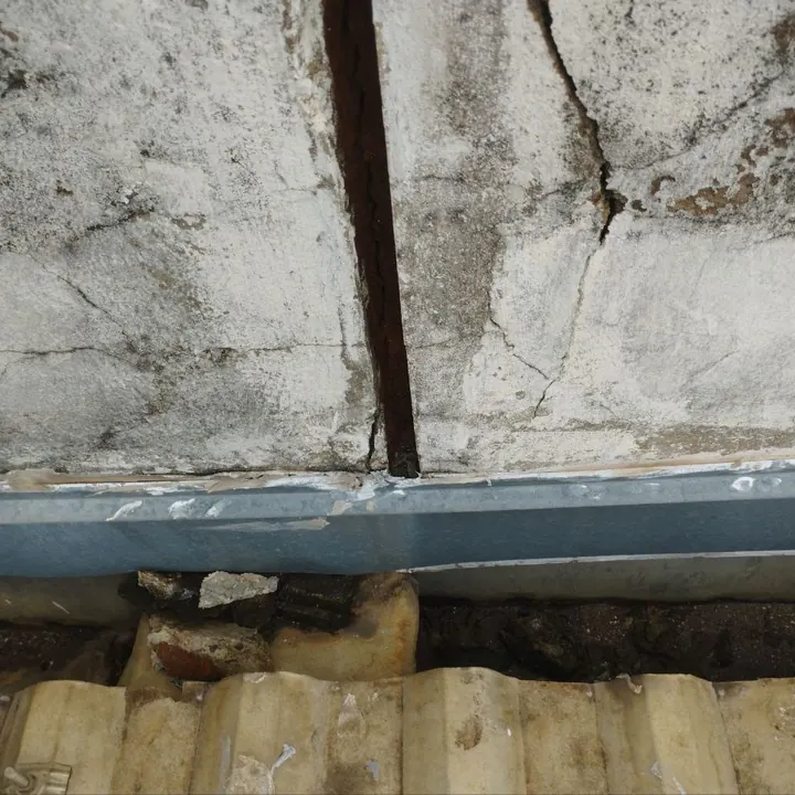 Calha antiga de concreto trincada, com ferrugem e entulho